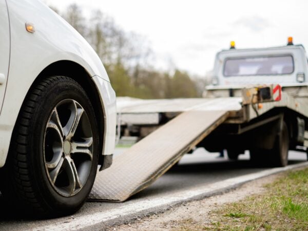 Flat bed tow truck loading a broken vehicle. Roadside service